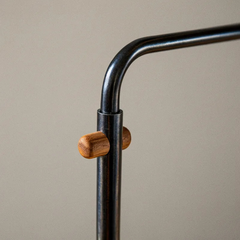 Close-up of a dark metal lamp arm with a small wooden peg