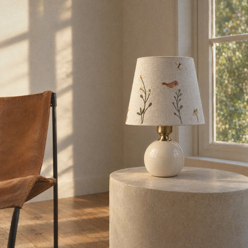 Cream ceramic table lamp with a bird and daisy embroidered shade, second room view