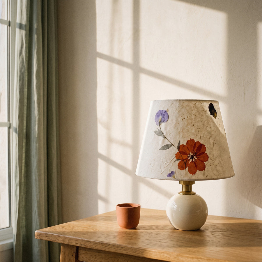 Cream ceramic table lamp with a pressed-flower paper shade in golden hour light