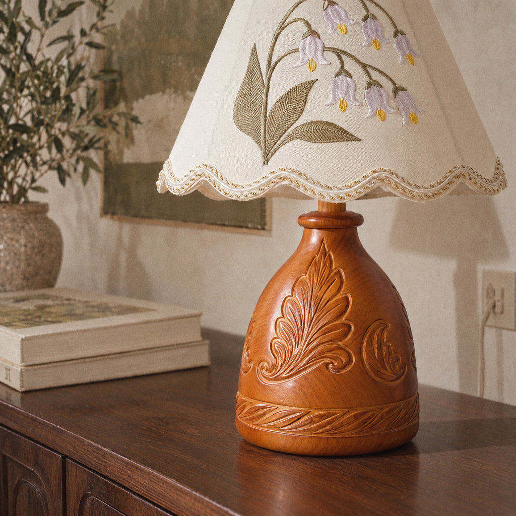 Medium close view of the embroidered lily of the valley sprig and gold-beaded scalloped hem
