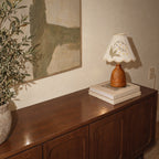 Lily of the Valley table lamp on a sideboard seen from above, with its shadow on the wall