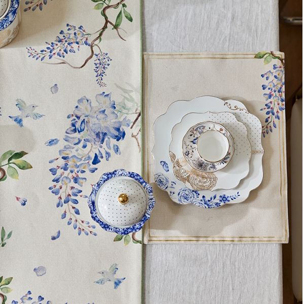 Decorative table runner with floral patterns and ceramic plates on a white background