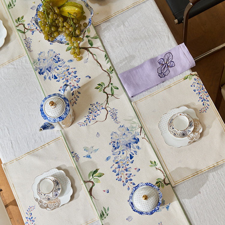 Decorative table runner with floral patterns and matching table settings on a wooden table.