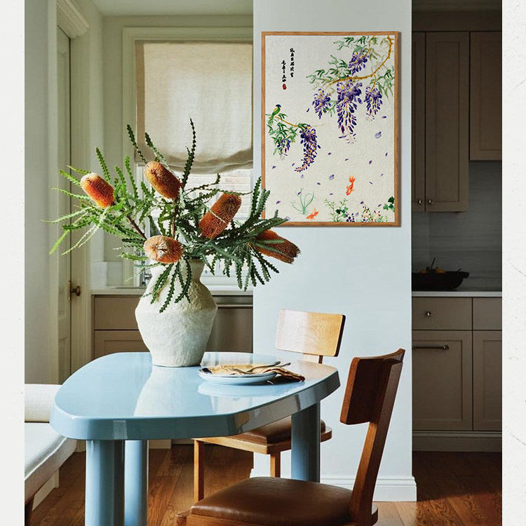 Dining room with a blue table, wooden chairs, and a vase of flowers on a white wall.