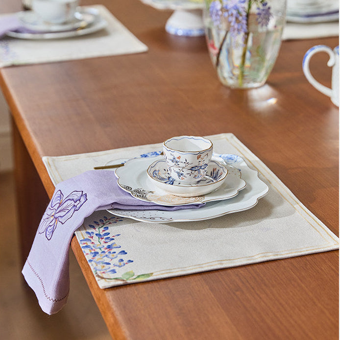 Dining table with plates, cups, and a vase on a wooden surface.