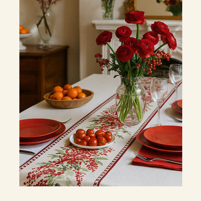 Dining table set with red roses, tomatoes, and a floral-patterned tablecloth.