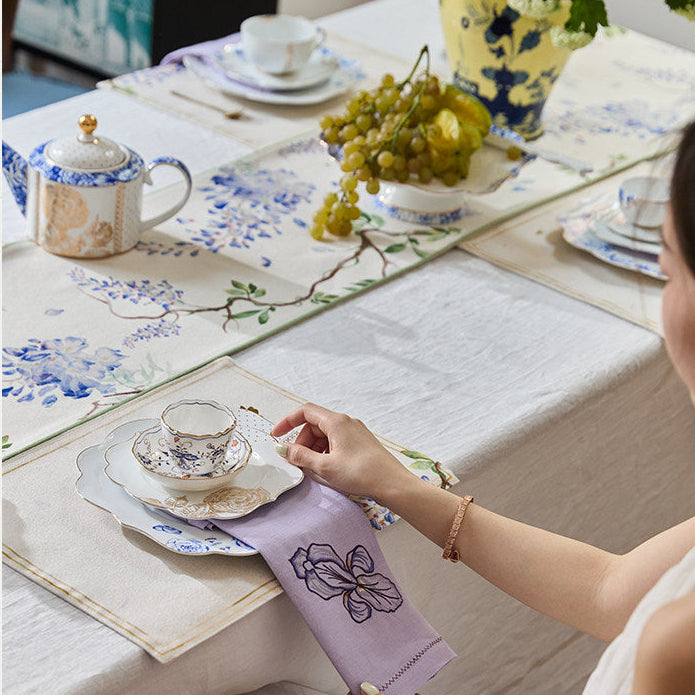 Person setting a table with decorative items and a teacup.