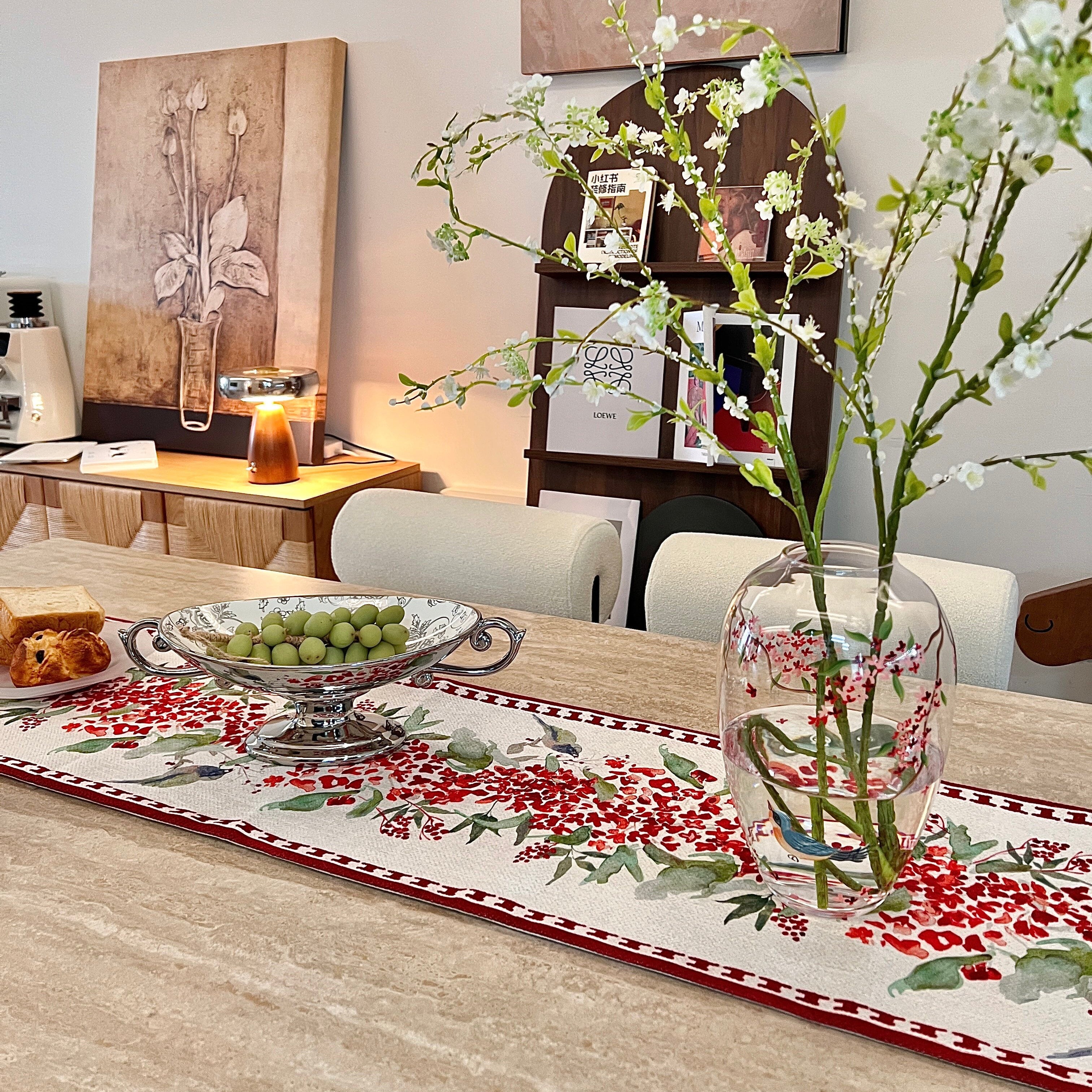 Dining room with a table set for a meal, featuring a vase with flowers and a decorative table runner.