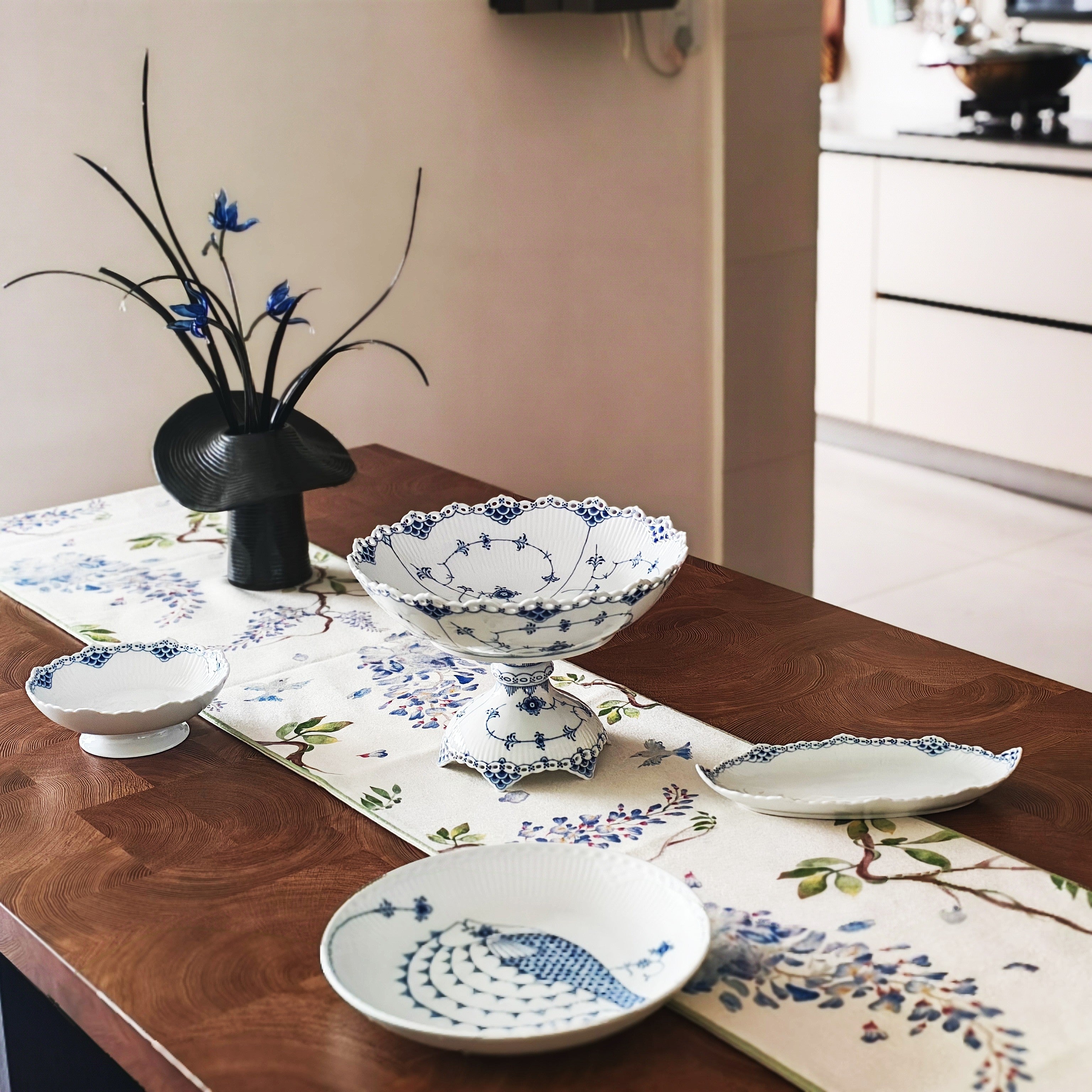 Decorative table setting with ceramic bowls and a vase on a wooden table.