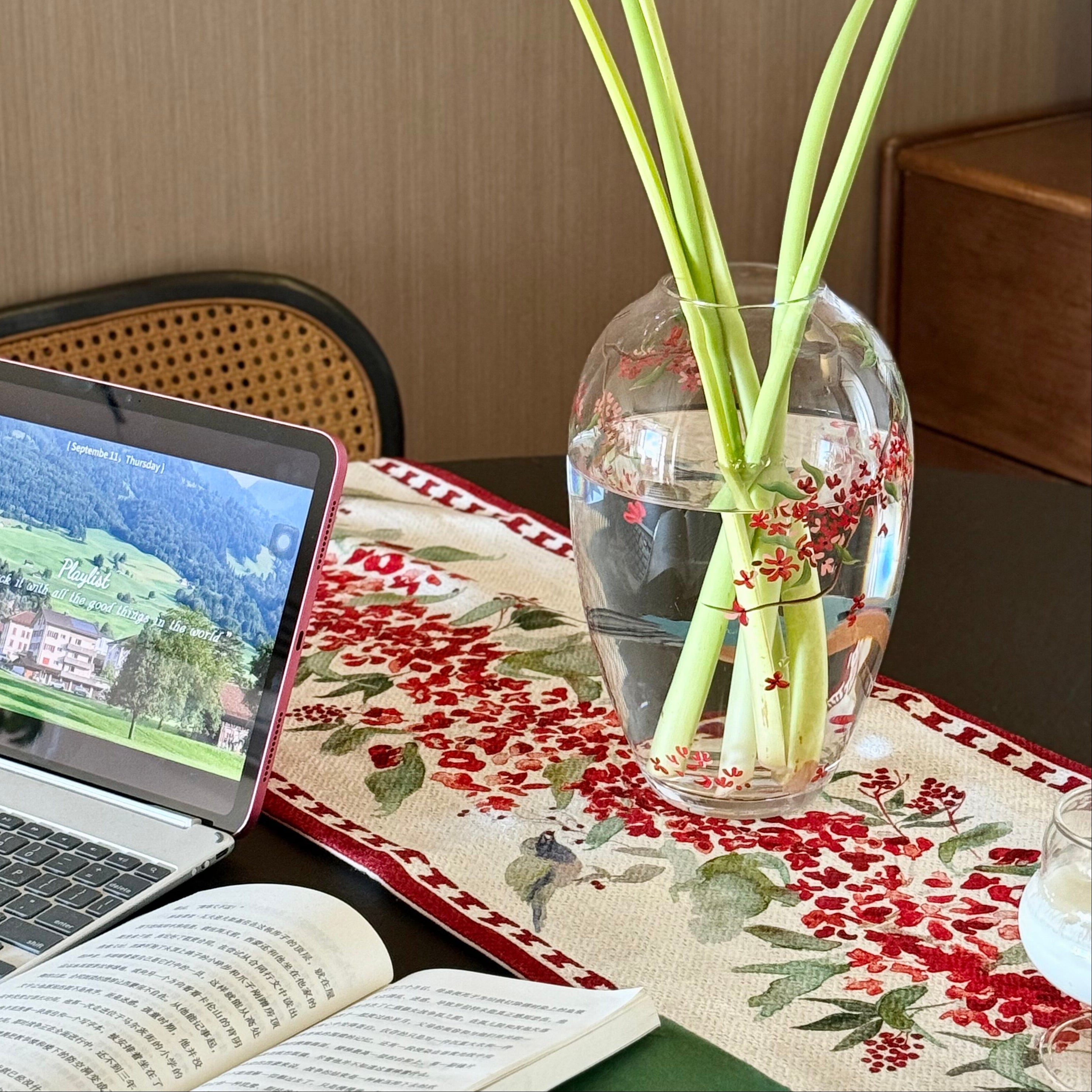 Vase with yellow flowers on a table next to a laptop and book