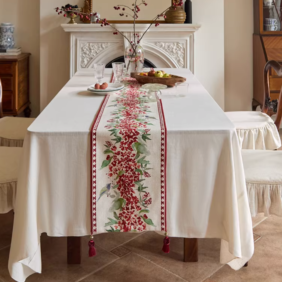 Dining room with a table set with a floral table runner, white tablecloth, and decorative items.