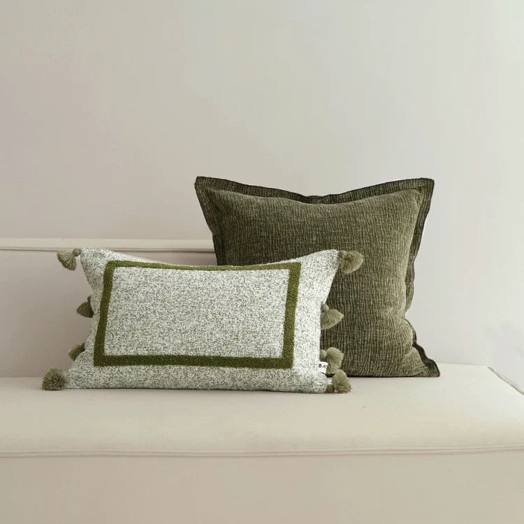 Two decorative pillows with green and white patterns on a neutral background