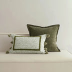 Two decorative pillows with green and white patterns on a neutral background