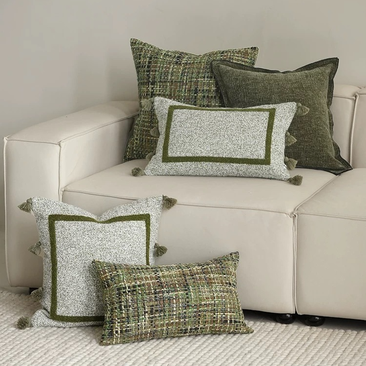 Collection of green and gray patterned pillows on a beige sofa.