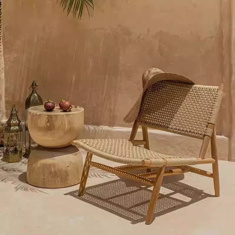 Wicker chair and ottoman with a small table against a beige wall.
