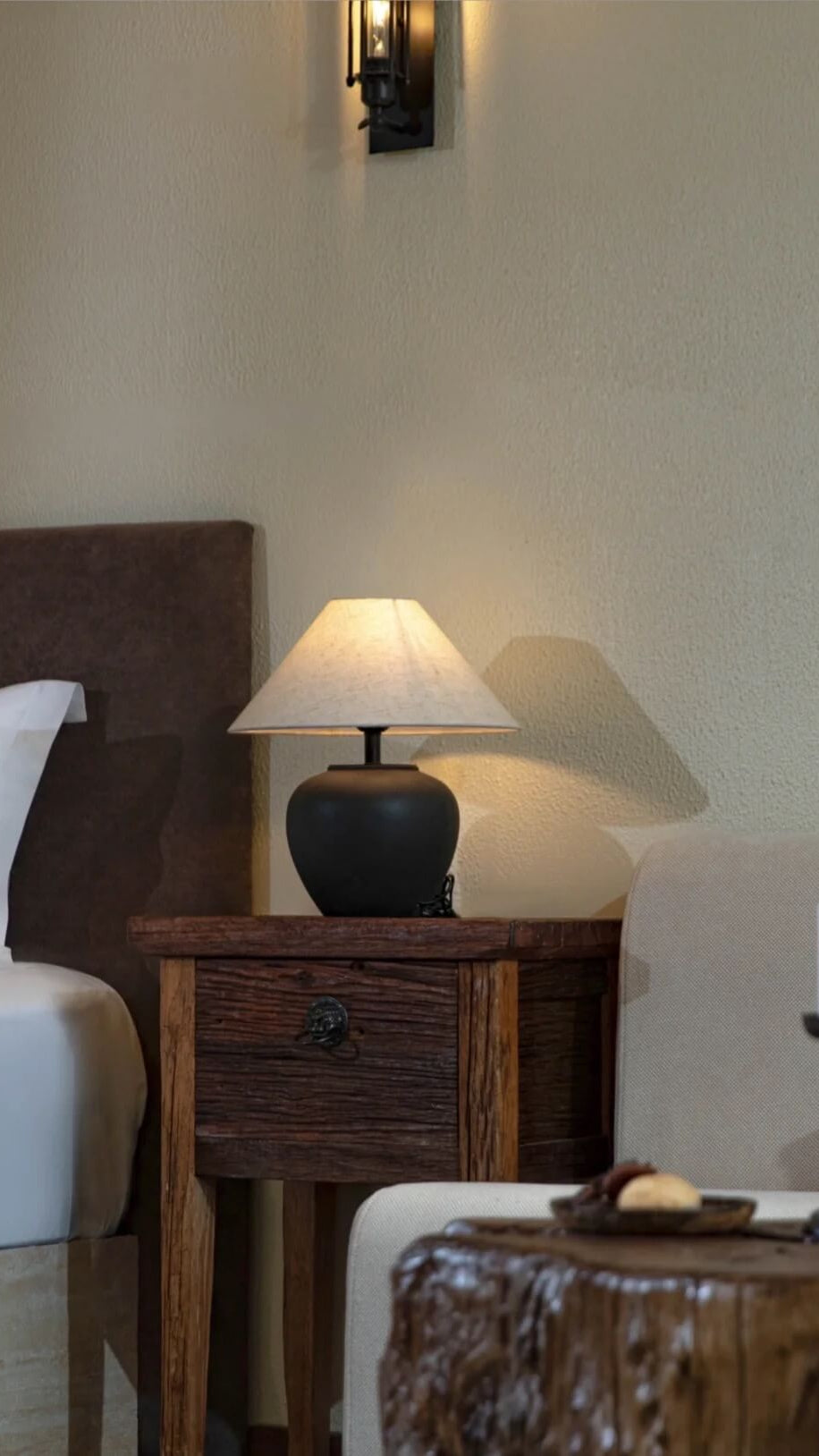 Bedroom scene with a wooden nightstand, lamp, and candle.