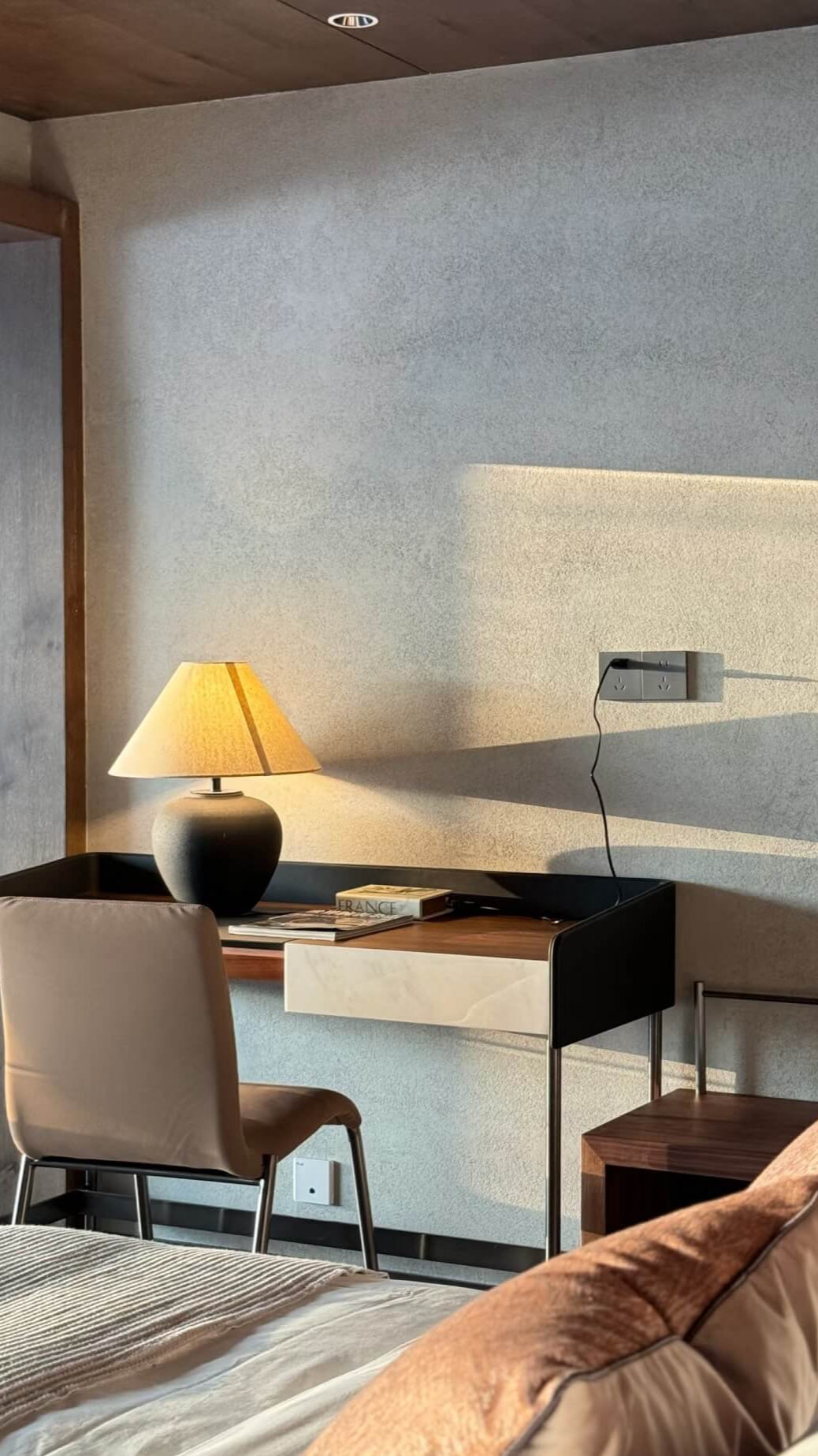 Modern bedroom with desk, chair, and a bde lamp against a gray wall.