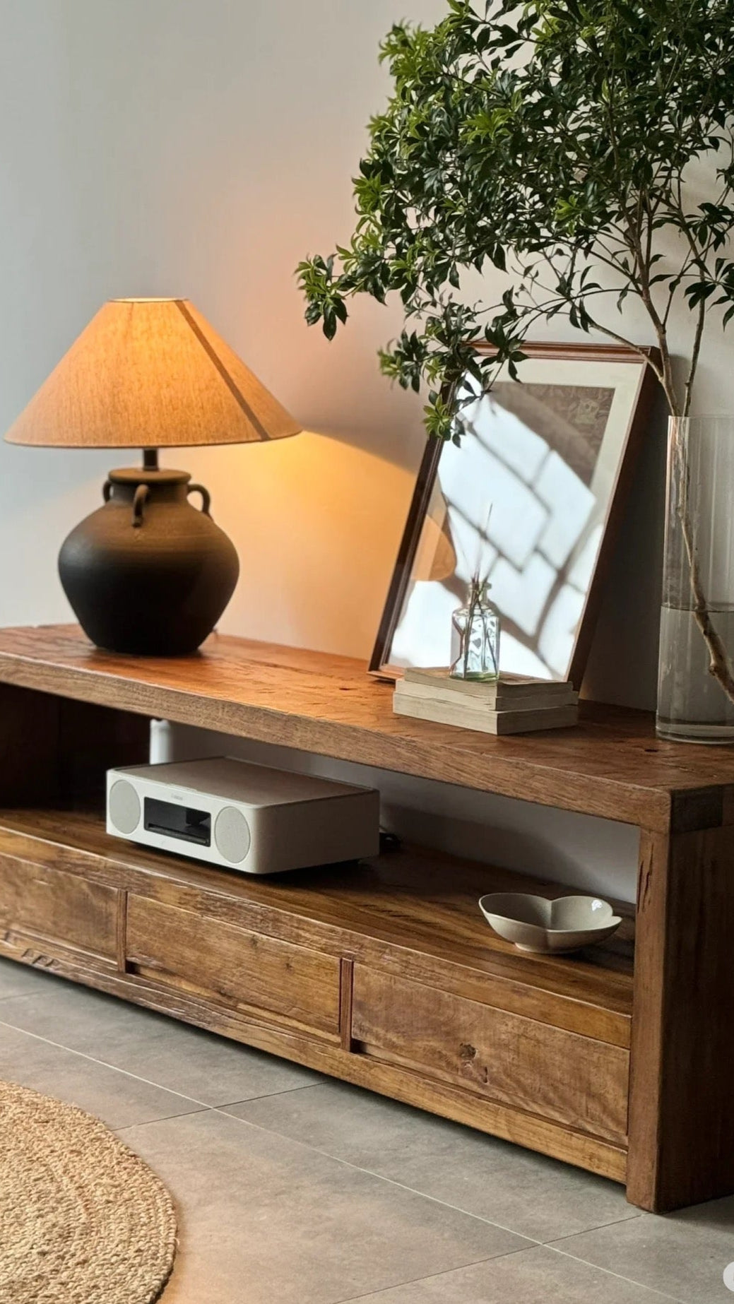 Wooden TV stand with decorative items in a living room setting