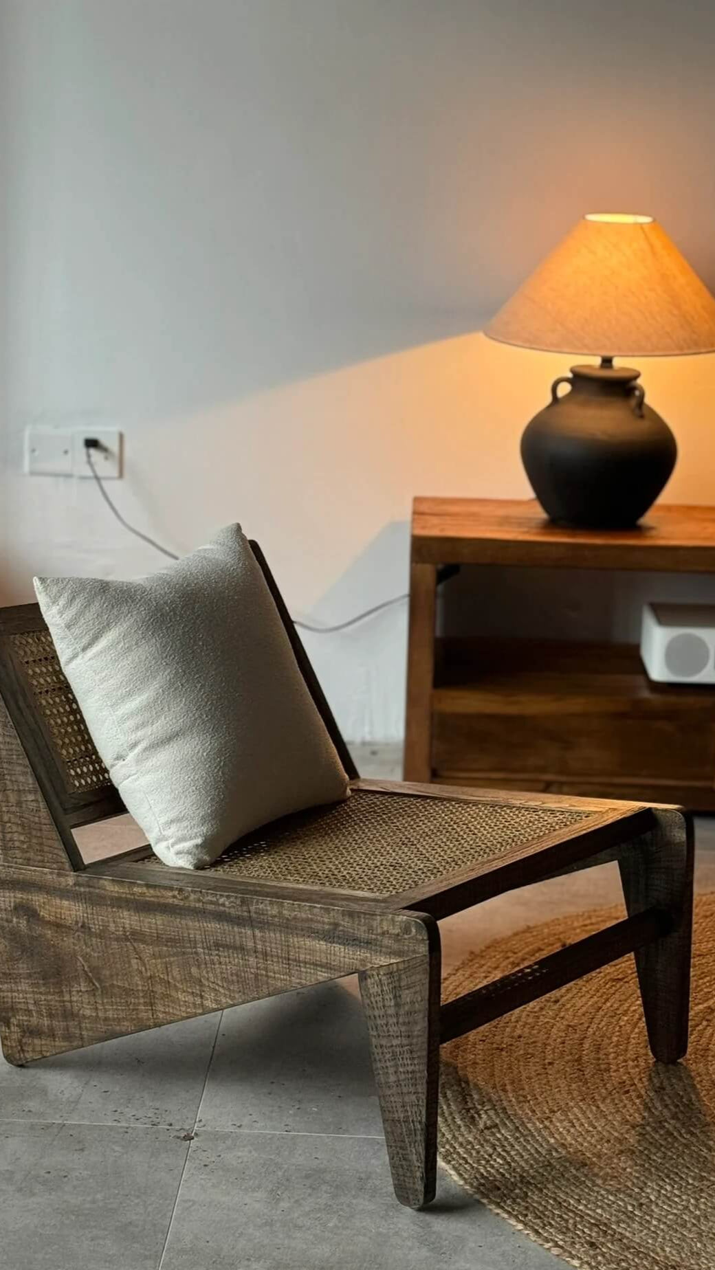 Wooden chair with a pillow in a room with a lamp and wooden cabinet.