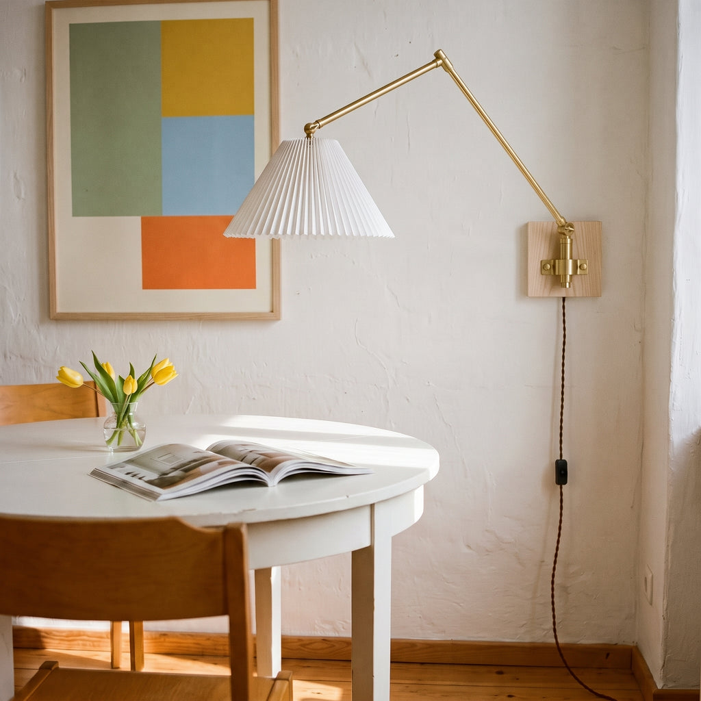 Swing arm wall sconce with a white pleated shade over a round dining table, a plug-in wall light for a small dining nook