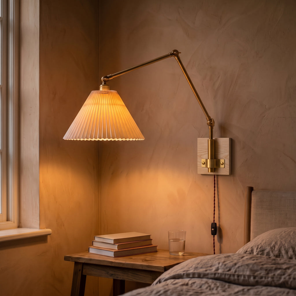 Bedside plug-in swing arm wall sconce with a lit pleated shade on a peach plaster wall above a wooden nightstand