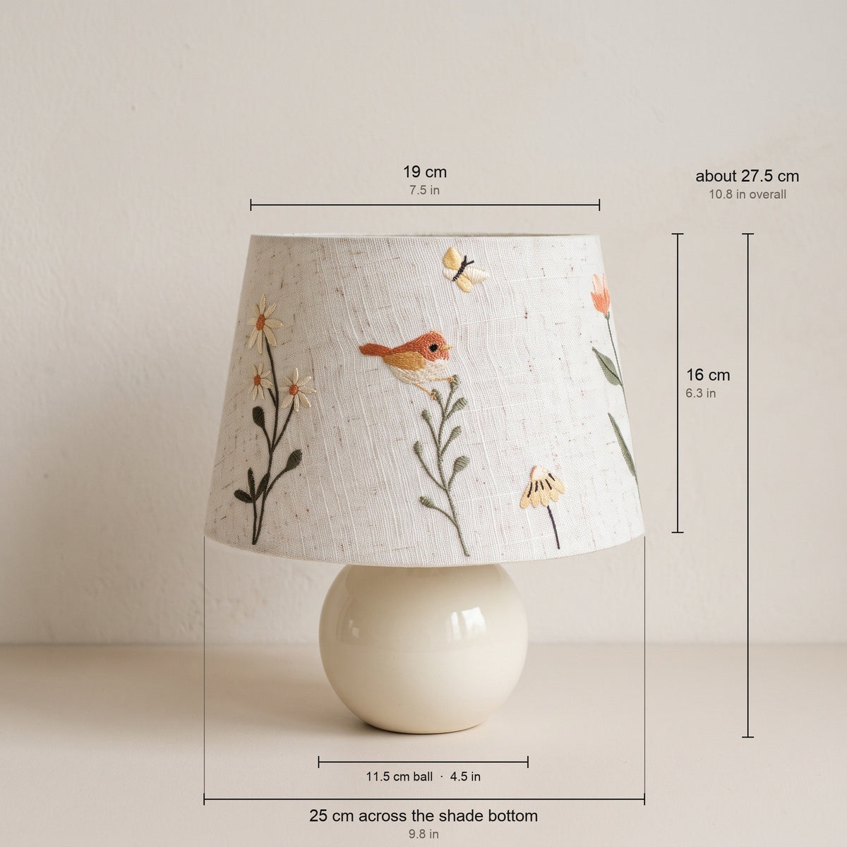 Bird and daisy embroidered table lamp with measurements: shade 19 cm across the top, 25 cm across the bottom and 16 cm tall; ceramic ball 11.5 cm; about 27.5 cm overall