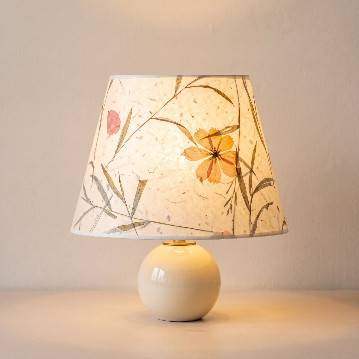 The cream ball lamp switched on, the petal paper glowing warm with the pressed cosmos and grasses showing through