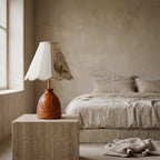 Lily of the Valley table lamp with an embroidered pyramid shade and carved reddish-amber wood base, in a room